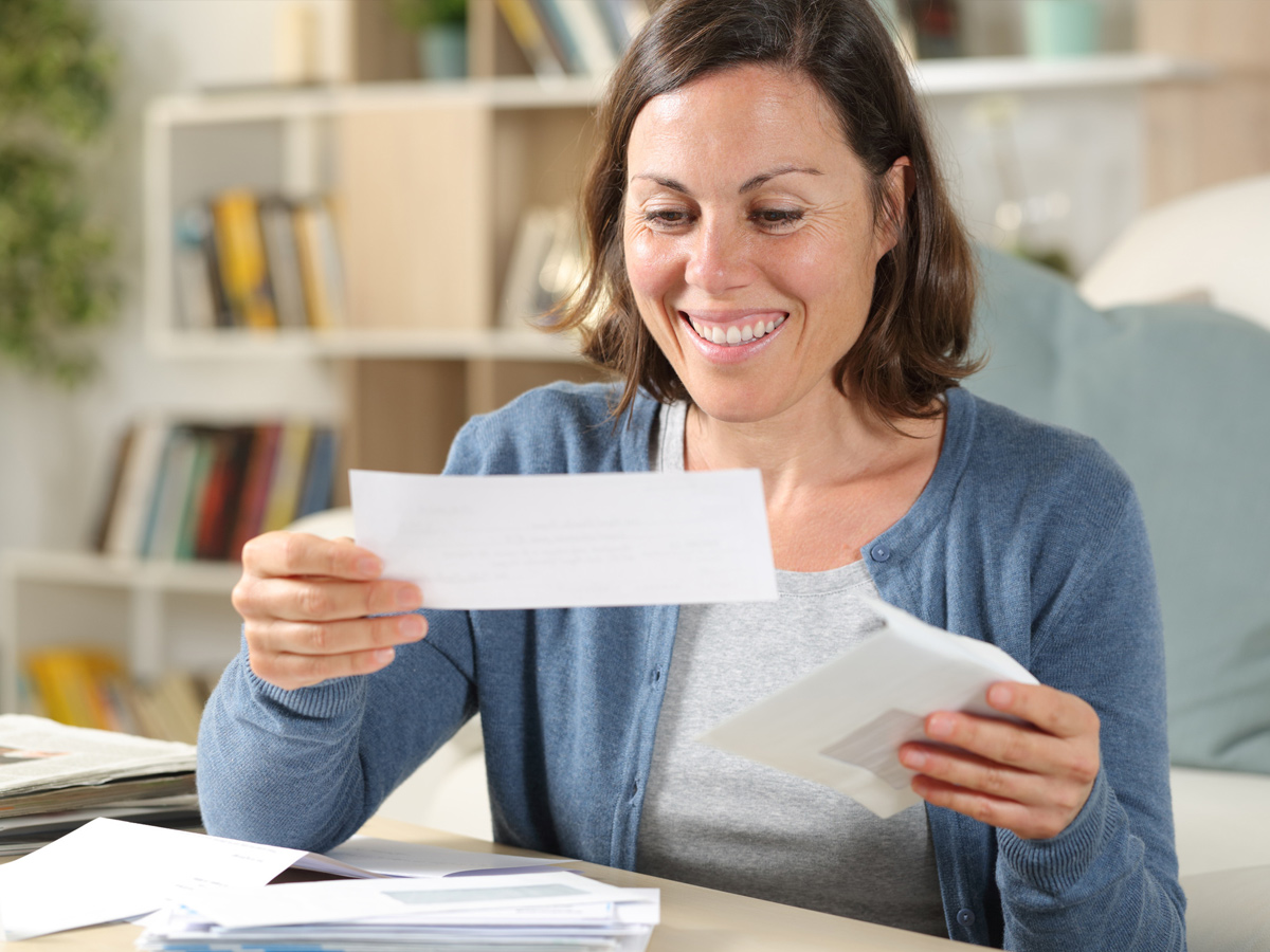 A woman looking at a utility bill and smiling.
